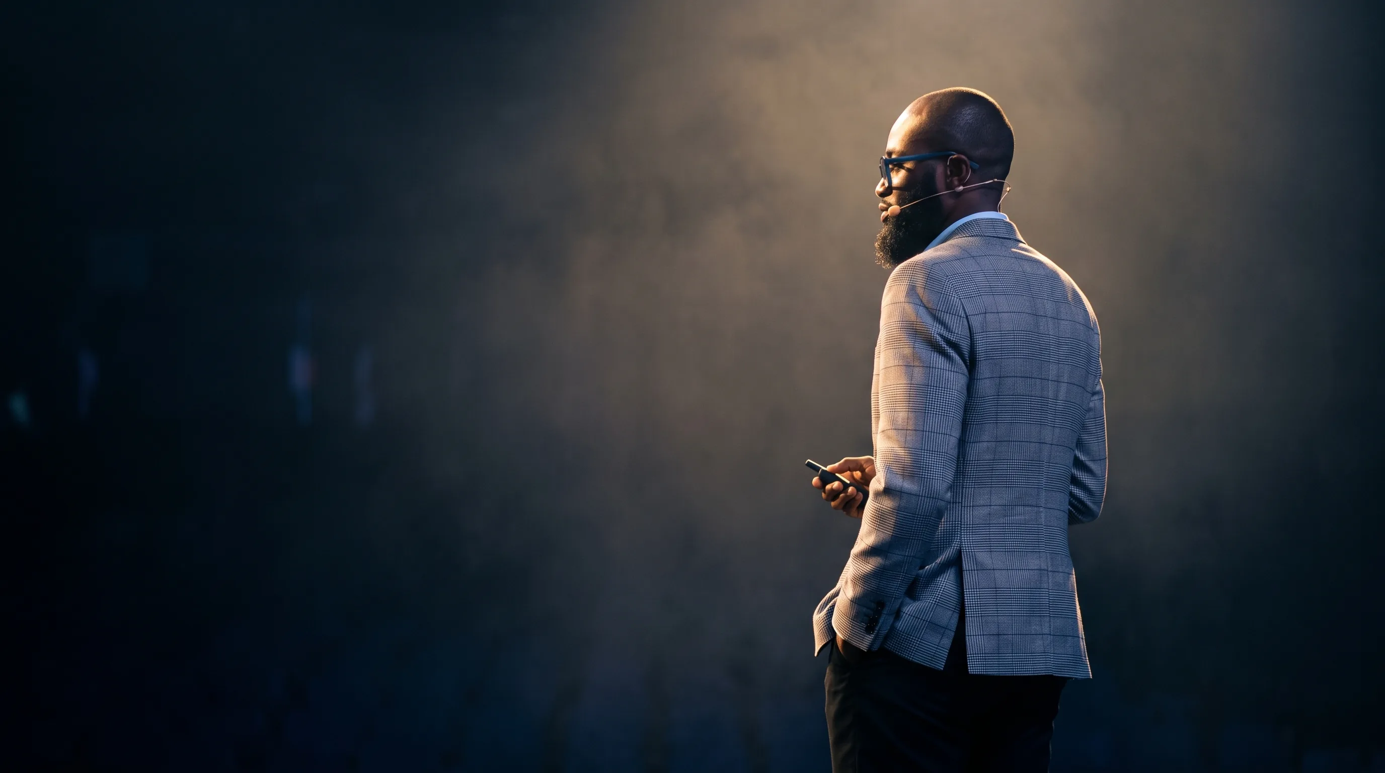 Dr. Kevin Abankwa on stage, speaking with a headset mic and presentation clicker